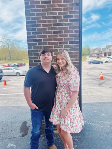 Customer wearing the floral Blooming Bright Ruffle Dress with striped ruffle details, standing outdoors.