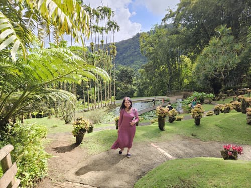 Customer walking in a lush garden wearing the flowy, ruby-colored Short Sleeves Light Silk Dress.