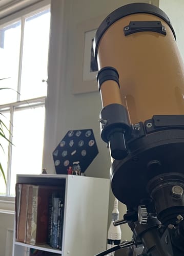 Reviewer's SpaceX Starship Pin Collection on its hexagonal display mount, shown on a shelf behind a telescope.