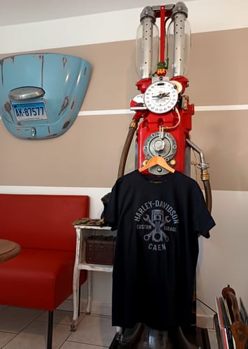 Photo d'un client montrant le T-shirt noir Custom Garage sur une pompe à essence vintage.