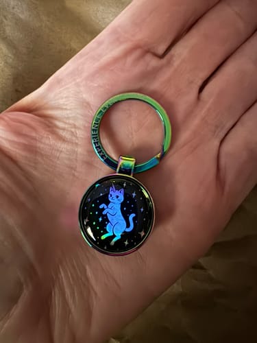 Customer holds the Caticorn Energy Zoxlox keychain in their palm, showing the glowing blue caticorn graphic.