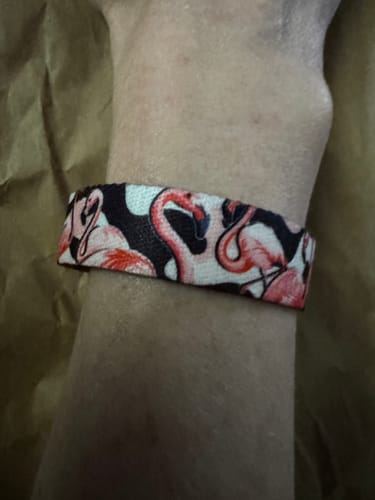 Close-up: Reviewer's wrist wearing the Pretty In Pink Bracelet with its detailed flamingo pattern.