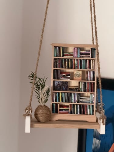 Rezensent zeigt ein dekoratives Hängeregal aus hellen Easy-Sticks Shine, auf dem ein Miniatur-Bücherregal steht.