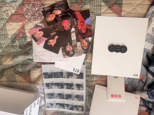 Customer's BTS Arirang album unboxed, showing photocards and other inclusions spread across a quilted surface.