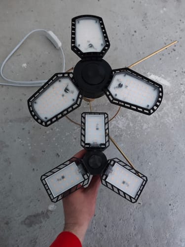 Rezensent vergleicht zwei schwarze LEDVANCE Highbay Blade Deckenlampen mit verstellbaren Flügeln und hält eine in der Hand.