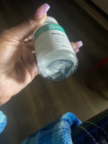 A reviewer holds up their empty bottle of Body Magic Chlorophyll Pills.