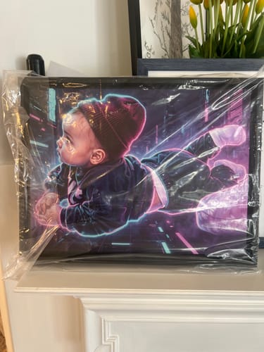 Customer's framed 'Your Original Artwork' canvas with a futuristic baby portrait, still in plastic wrap on a mantel.