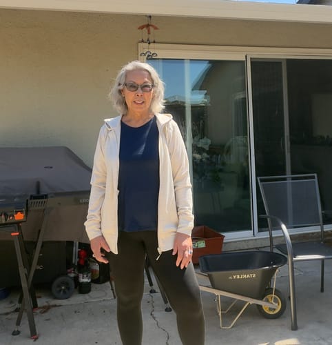 Reviewer standing on an outdoor patio wearing the Ryann Hoodie in Cream Heather open over a dark shirt.