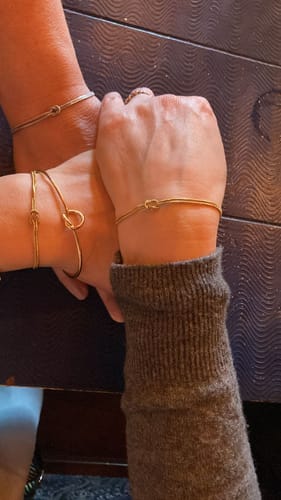 Customer and friends wearing matching gold and silver knot bracelets.