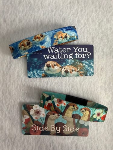 Customer's 'Water You Waiting For?' and 'Side By Side' Otter Pack bracelets displayed with their matching collector cards.