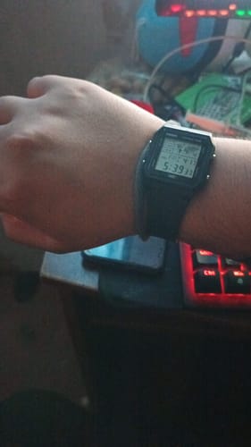 Cliente usando su Reloj Casio Vintage negro en la muñeca en un escritorio.