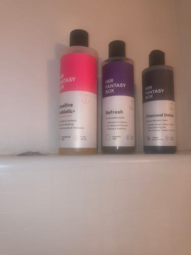 Customer's three Her Fantasy Box washes, including Refresh, Sensitive Probiotic+, and Charcoal Detox, on a bathroom ledge.