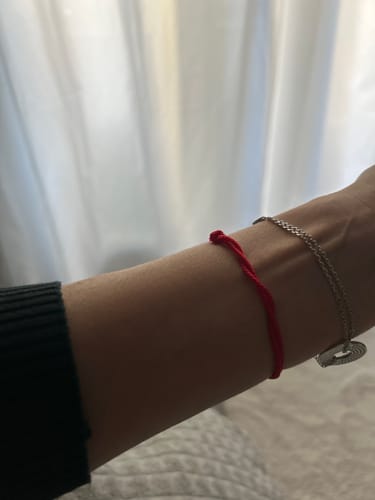 Client avec le Bracelet Porte Bonheur 'Tibétain' rouge porté au poignet.