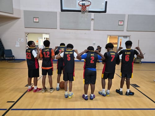 Reviewer's basketball team on a court, showing the back of their custom black basketball jerseys with names and numbers.