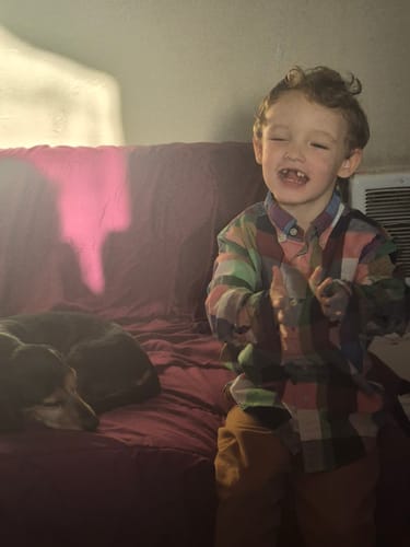 Reviewer's son, subject of the NeuroBrocc Gummies review, smiling peacefully on a couch next to a dog.