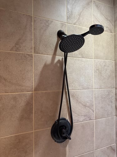 Customer's black dual showerhead with the replacement shower hose mounted on a tiled wall.