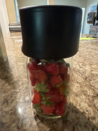 Customer using the black Mason Genie Vacuum Sealer on a glass jar filled with fresh strawberries.