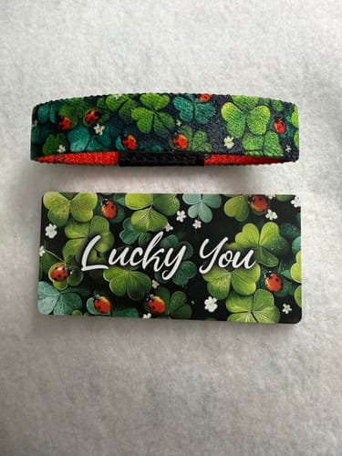 Customer's Lucky You Bracelet with a colorful clover and ladybug pattern, displayed with its matching collector's card.