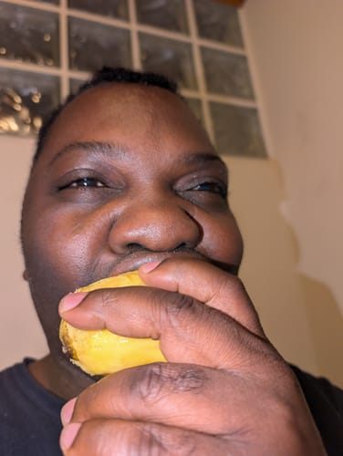 Nahaufnahme eines Rezensenten, der eine saftige Mango Emeraude Bio isst.