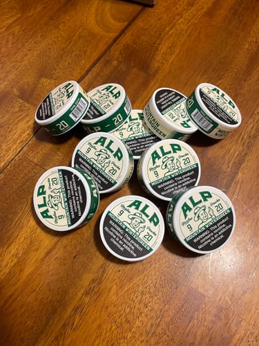 Customer's multiple tins of Mountain Wintergreen Nicotine Pouches scattered across a wooden table.