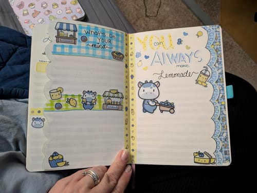 Reviewer's open journal decorated with cute Blueberry Lemonade stickers featuring a cow pulling a cart.