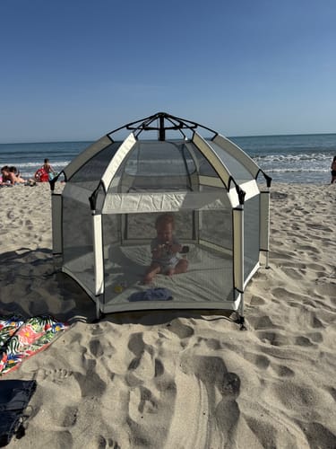 Customer's Pop 'N Go Playpen set up on a sandy beach with a baby sitting inside.