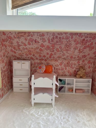 Customer's Adelina Wallpaper with a whimsical pink pattern used to decorate the walls of a dollhouse bedroom with white furniture.