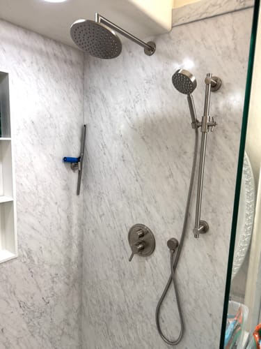Customer's installed 2-Handle Shower System with a brushed metal finish, showing the rain head and handheld unit on a marble wall.