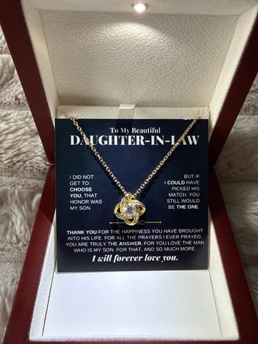 Reviewer's gold-tone Love Knot Necklace in its illuminated mahogany gift box, resting on the message card.