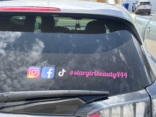 Customer's custom social media decal with Instagram, Facebook, and TikTok logos and a pink username on a car's rear window.