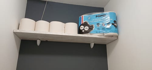 Client montrant des rouleaux de papier toilette Confort et le paquet sur une étagère.