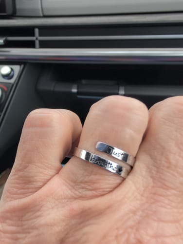 Customer's hand wearing the silver Just Breathe Ring, showing the 'Just breathe' engraving.