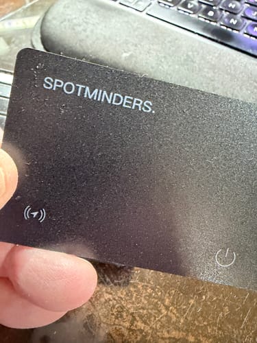 A reviewer holding the thin, black SPOTMINDERS tracking card in their hand.