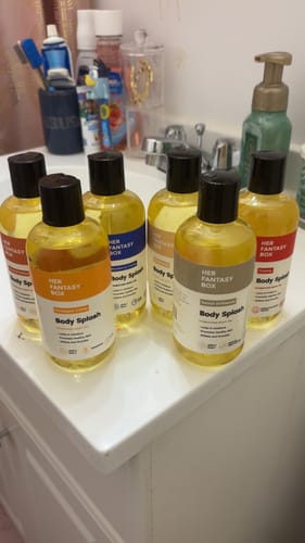 Customer's six bottles of Sweet Skin Body Splash Oil arranged on a bathroom sink.