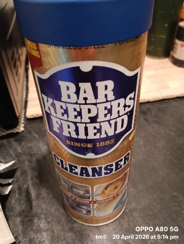 Customer's container of Bar Keepers Friend Cleanser with a blue lid, sitting on a dark kitchen counter.
