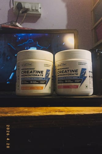Customer's two white tubs of Wellcore Micronised Creatine Monohydrate sitting side-by-side on a desk.