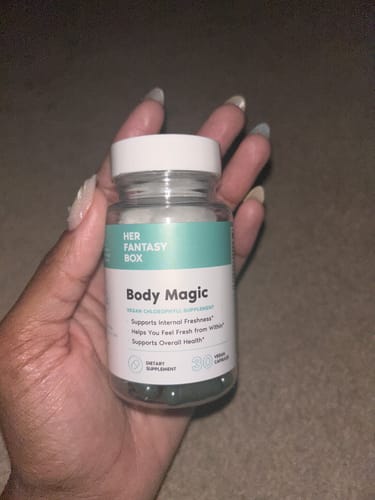 Customer holding a clear bottle of Body Magic Chlorophyll Pills, showing the dark green capsules inside.