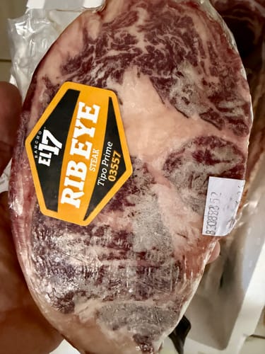 Cliente sostiene un steak tipo Prime, grueso y marmoleado, en su empaque al vacío.