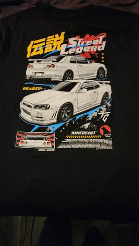 Customer's black Street Legend Tee laid flat, showing the detailed R34 sports car graphic on the front.