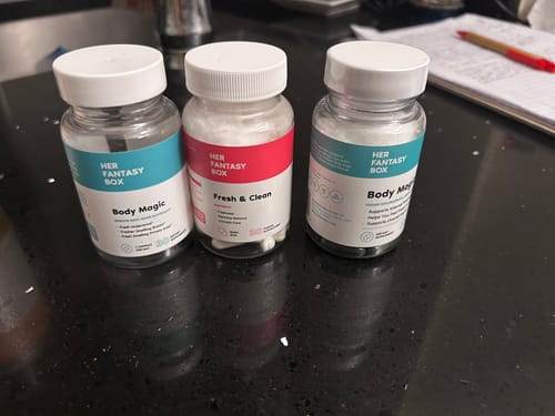 Customer's two bottles of Body Magic Chlorophyll Pill and another supplement bottle on a black counter.