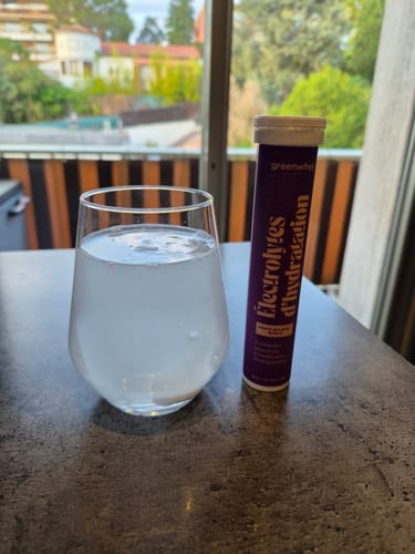 Pastille d'Électrolytes d'hydratation d'un client se dissolvant dans un verre d'eau à côté du tube.