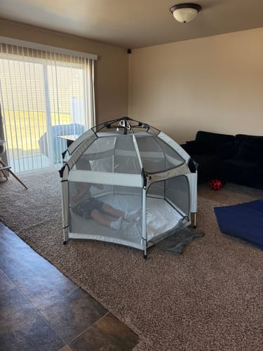 Reviewer relaxing inside their spacious Pop 'N Go LUXE Playpen set up in a living room.