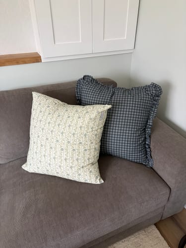Customer's pillows with Premium Faux Down Inserts, looking full and plush on a gray couch.