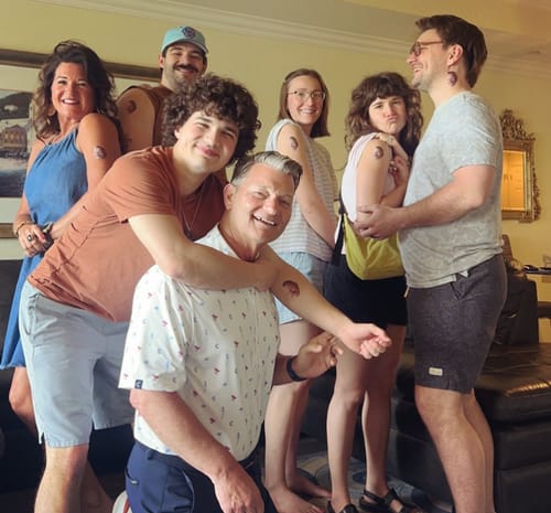 A group of happy customers celebrating together, all wearing a Custom Photo Face Temporary Tattoo on their arm.