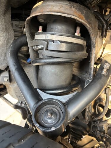 A close-up of the customer's original upper control arm installed on their truck, shown for comparison.