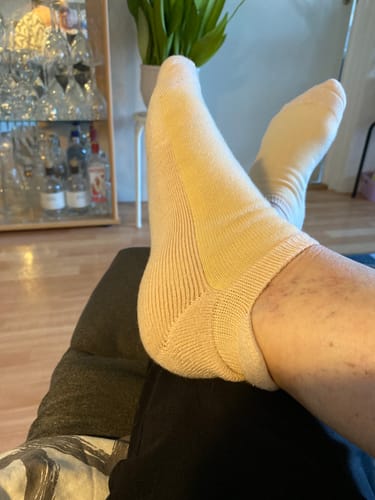 Kund som vilar med fötterna i ett par ljusa Diasocks ankelstrumpor, med fokus på strumpans häl.