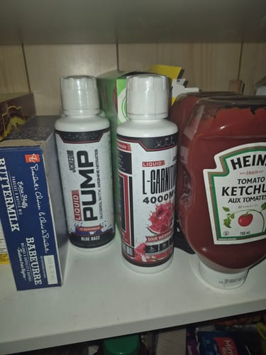 Reviewer's bottle of Liquid L-Carnitine 4000MG in Sour Watermelon flavor, shown on a pantry shelf with other items.