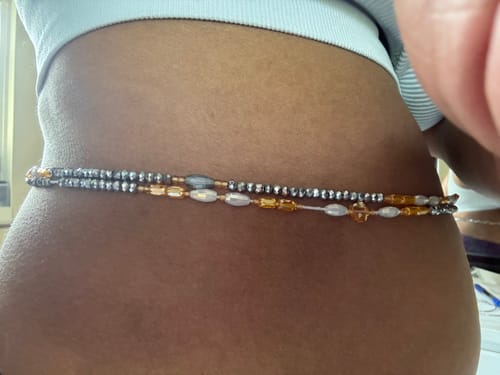 Close-up of a customer wearing two strands of the Silver Sparkle waist beads, featuring silver, gold, and white beads.