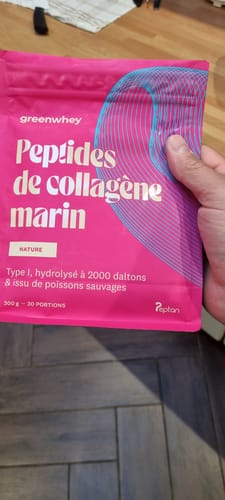 Un client tient le sachet rose vif de Peptides de Collagène Marin dans sa main.