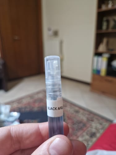 Primo piano di un recensore che tiene in mano un campione del profumo Black Afgano Nasomatto.
